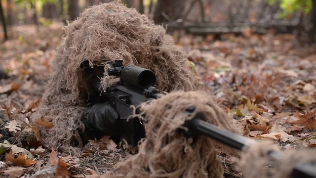 Close-up of aiming hidden sniper/Masked sniper in camouflage uniform aim from assault rifle
