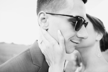 groom kissing bride in field