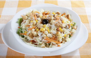 Delicious salad of fresh vegetables with ham, cheese and egg, served in a white bowl.