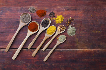 Wooden spoons full of aromatic herbs and spices on a wood cuttin
