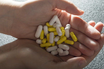 Stack of different pills in both hands isolated on grey background