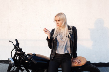 Naklejka na ściany i meble woman sitting on vintage motorcycle and smoking sigarette