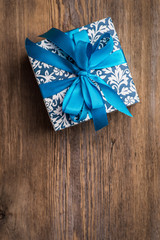 Vintage christmas gift box with blue bow on wooden surface