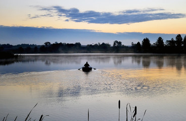 A fisherman in a boat sailing in the morning mist