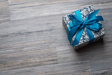 Vintage christmas gift box with blue bow on wooden surface