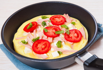 omelet with ham and cheese in a frying pan