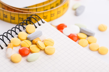 Pills, notepad and measuring tape on the white table