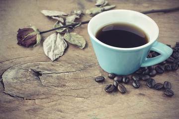 Cup of coffee with dried rose on old wooden table