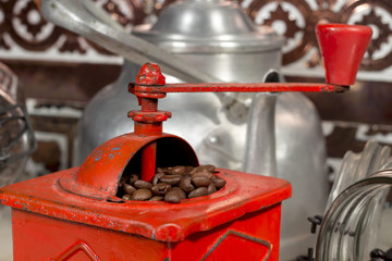 Roasted coffee beans being grinded into a traditional manual coffee grinder