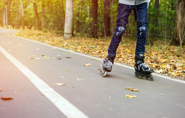Teenager in motion rollerblading in autumn park