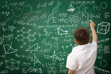 schoolboy writing math formula on blackboard