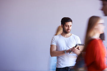 student working on tablet, people group passing by