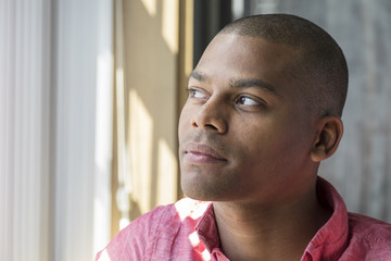 Portrait of a young black man, looking out a window