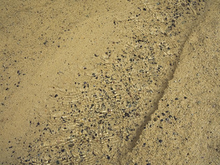 Brook on the sand beach low water. Rolling grains. Background like the aquarium. Orzola bay, Lanzarote, Canary Islands