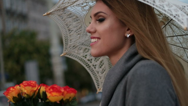 blonde woman holding a bunch of roses in a rainy day 