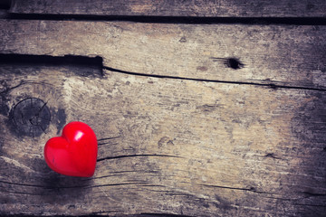Red heart on aged wooden background.