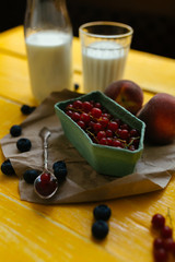 Красная смородина с молоком на желтом столе