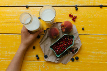 Персики и красная смородина с молоком на желтом столе