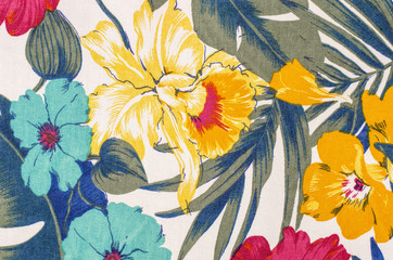 Floral pattern on white fabric. Colorful exotic flowers with green and blue leaves print as background.