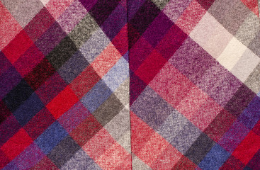Scottish tartan pattern. Red plaid print as background. Colored lines and square pattern. Scottish checked fabric with seam.