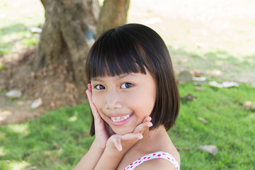 Fototapeta premium Happy little girl having fun and smiling at the park