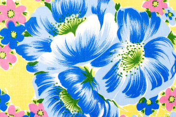 Fototapeta na wymiar Floral pattern on yellow fabric. Colorful exotic big blue flower with small pink flowers print as background.