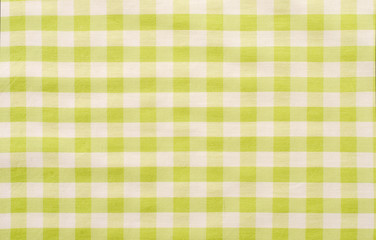 Close up on checkered tablecloth fabric. Green with white tartan square pattern as background.