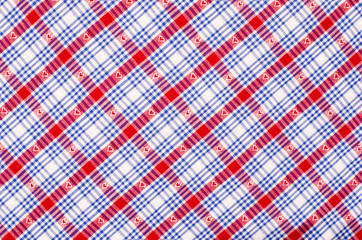 Close up on checkered tablecloth fabric. Red and blue with hearts tartan square pattern as background.