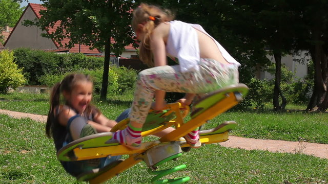 little girls ride on a swing in the park