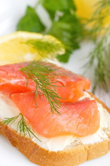 Sandwich with smoked salmon, cream cheese and lemon on plate