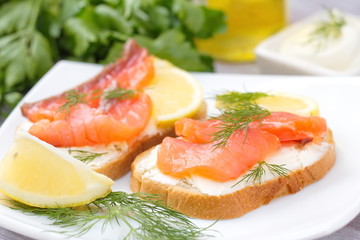 Sandwich with smoked salmon, cream cheese and lemon on plate