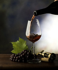 Glass with red wine and grapes on the wooden table
