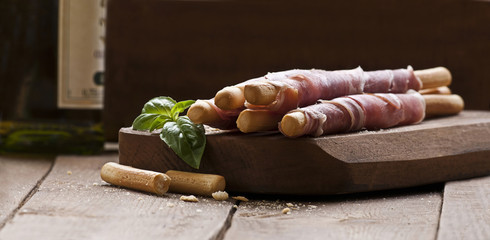 Photo of parma ham rolled on grissini bread sticks.