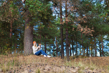 girl sits under a tree in the forest and keeps the dog in her arms