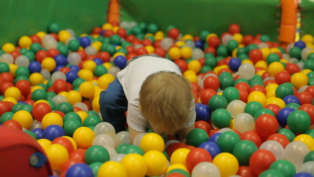 Little smiling boy playing in colorful balls