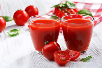 Glasses of tomato juice on wooden table, closeup
