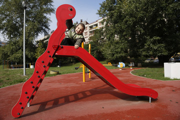Little boy playing in park with child slide