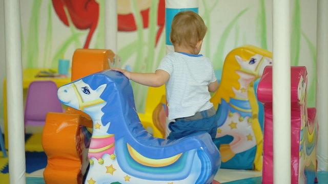 Smiling child riding a toy horse carousel