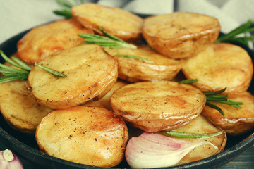 Delicious baked potato with rosemary in frying pan close up