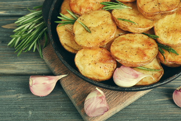 Delicious baked potato with rosemary in frying pan on table close up