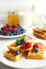 Sweet homemade waffles with forest berries and sauce on table background
