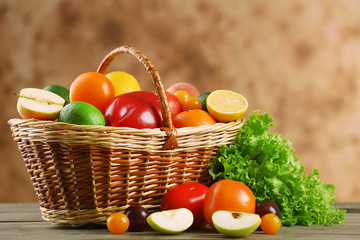 Heap of fresh fruits and vegetables in basket on wooden table close up