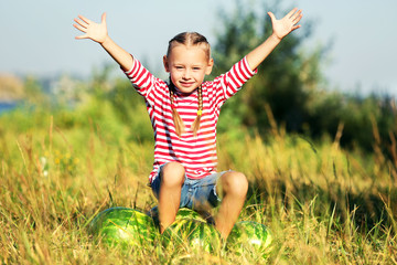 Small girl with watermelons on lawn