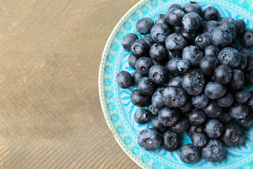 Fresh blueberries on plate on wooden table close up