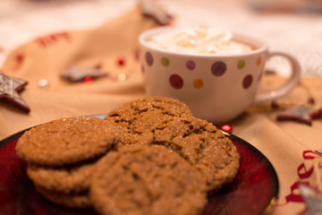Homemade molasses cookies on Christmas serving plate with mug of hot chocolate