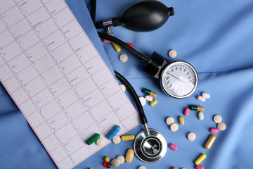 Blood pressure meter, pills and stethoscope, on blue uniform background