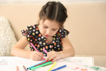 Cute little girl drawing picture on home interior background