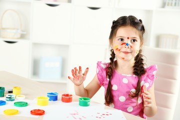 Cute little girl painting picture on home interior background