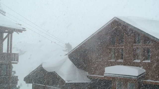 Snow blowing by a chalet in the French Alps. 