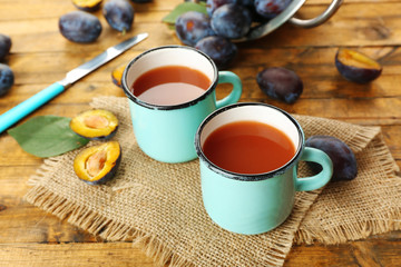 Plum Juice in mugs with fresh fruits
